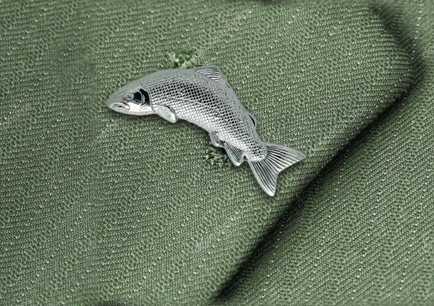 Die cast, palladium plated salmon lapel badge on a tweed jacket.