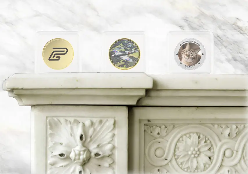 A range of personalised coins in square, protective capsules on a mantelpiece.